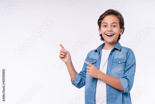 Amazed young male kid pointing at copy space isolated over white background photo