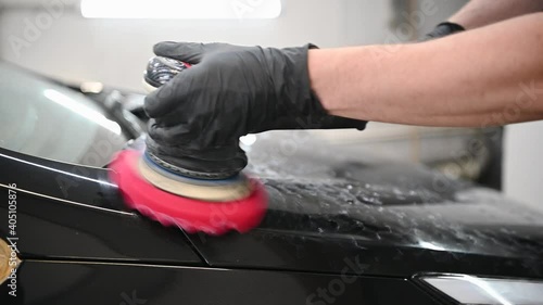 Car detailing - hands with orbital polisher in auto repair shop in slow motion.