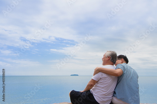 Real view of Senior retirement age and son sitting with ocean background. asia father and son feeling happiness looking blue sky and sea relax time