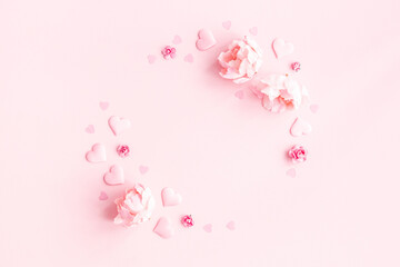 Valentine's Day background. Wreath made of pink flowers, hearts on pastel pink background. Valentines day concept. Flat lay, top view, copy space
