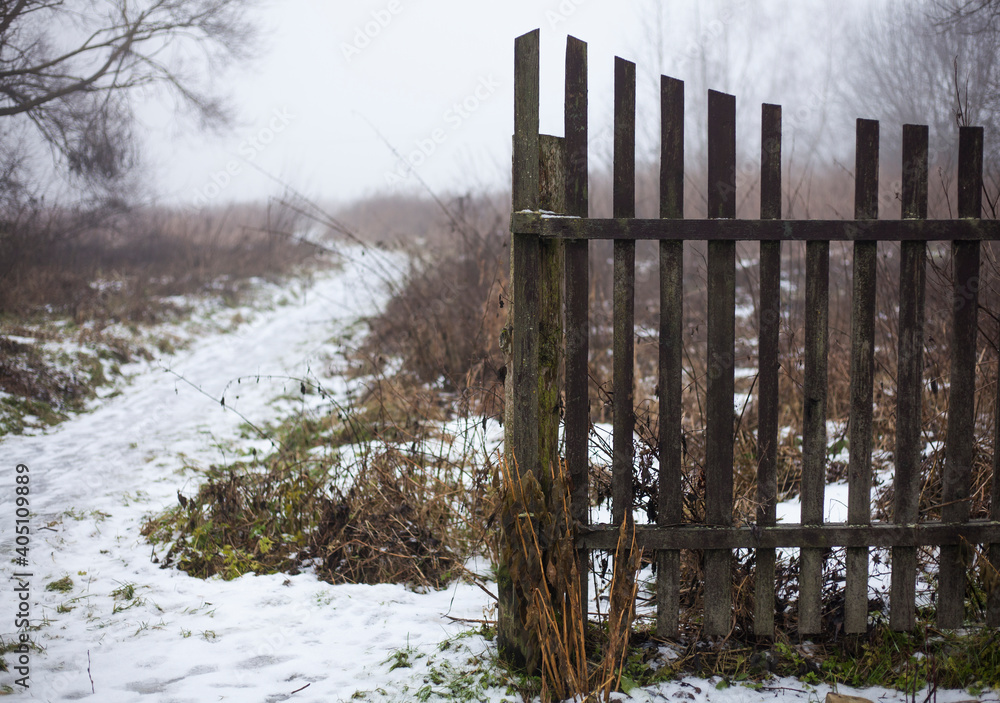 Fototapeta premium foggy winter day.snowy path to the fog.old fence.rural landscape