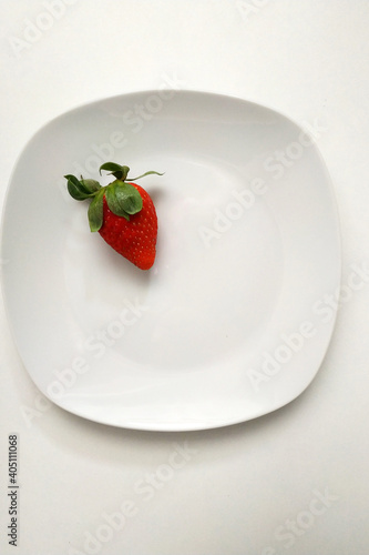 Juicy strawberries on a plate alone, a favorite fruit for bakery products, a delicious dessert, a fragrant berry with green leaves.