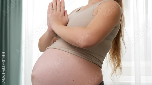 Beautiful smiling pregnant woman in sportrs outfit practicing yoga and meditating at big window. Concept of healthy lifestyle, healthcare and sports during pregnancy photo