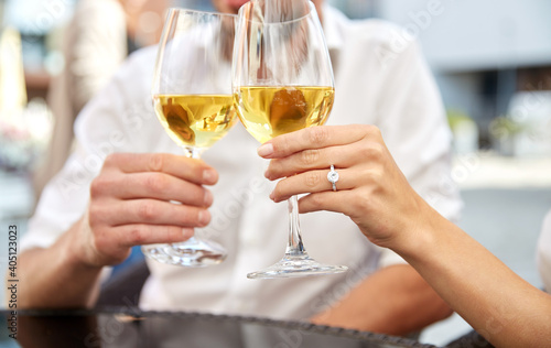love, dating and people concept - close up of couple clinking wine glasses and celebrating engagement at restaurant