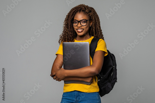Friendly african woman high school student typing on portable computer isolated on gray background photo