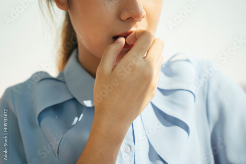 Asian woman bitting nail. Portrait of worried scared woman in formal shirt.