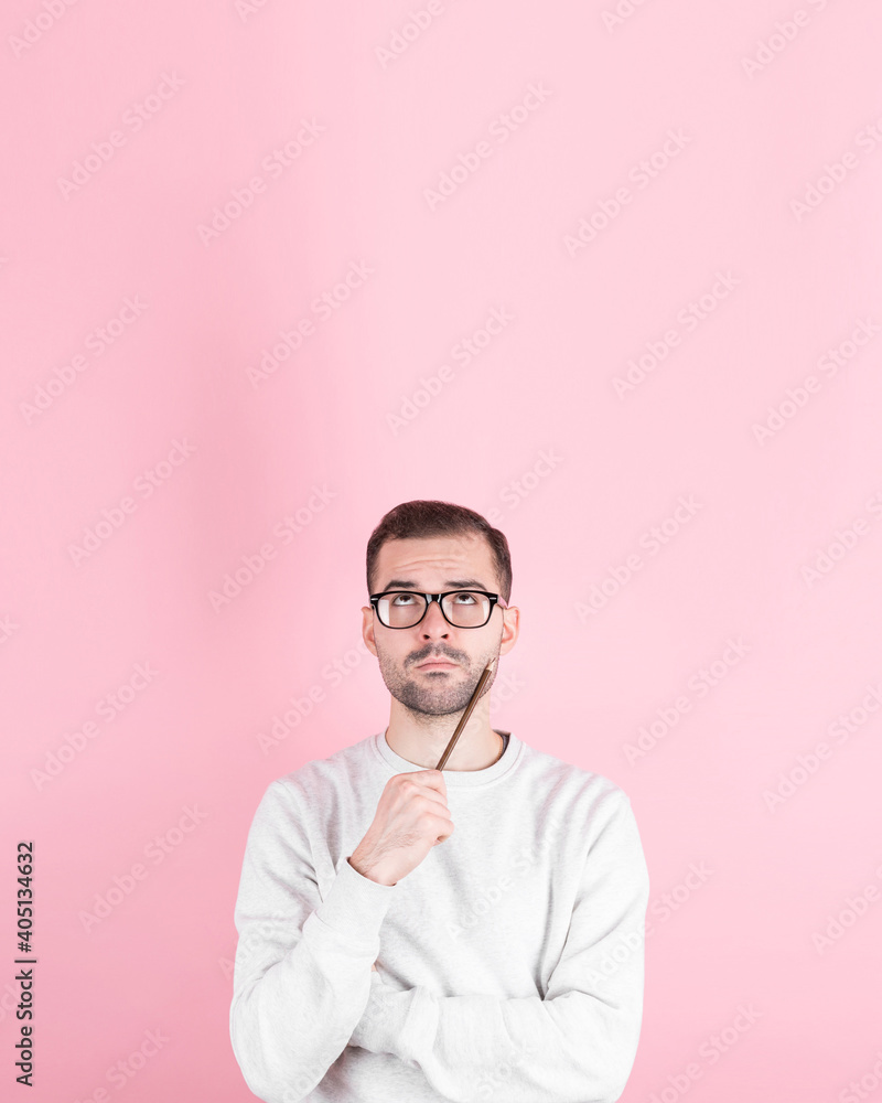 Portrait of young man thinking with pencil to her head and looks to the side Portrait of young man thinking with pencil to her head and looks to the side