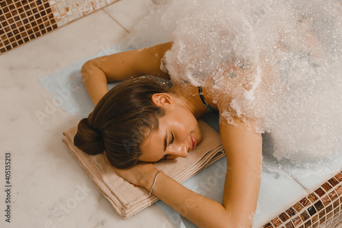 Luxurious relaxing foam massage in the Turkish hammam. Masseur crumples woman's skin in hammam photo
