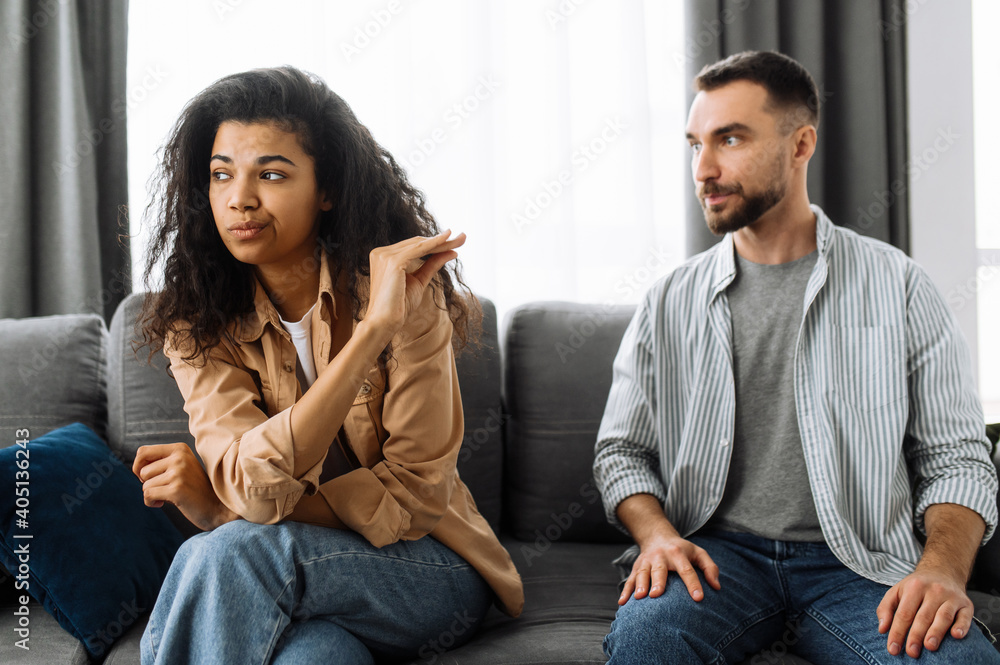 A married couple finds out the relationship, a quarrel between lovers. Multiracial couple in love quarreling at home on couch over household or financial problems. Domestic family conflicts concept A married couple finds out the relationship, a quarrel between lovers. Multiracial couple in love quarreling at home on couch over household or financial problems. Domestic family conflicts concept