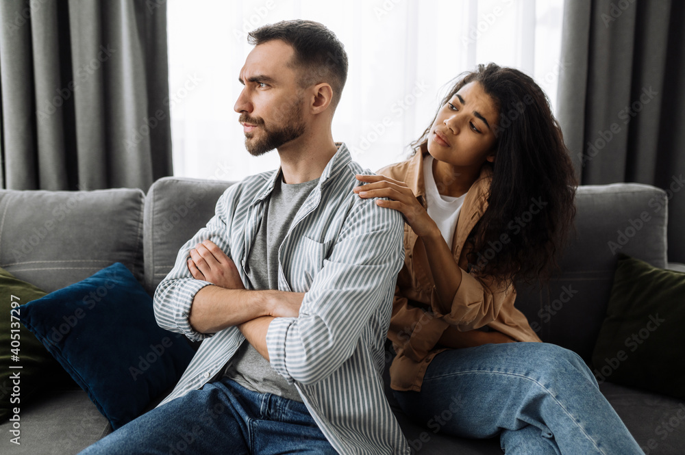 A married couple finds out the relationship, a quarrel between lovers. Multiracial couple in love quarreling at home on couch over household or financial problems. Domestic family conflicts concept A married couple finds out the relationship, a quarrel between lovers. Multiracial couple in love quarreling at home on couch over household or financial problems. Domestic family conflicts concept
