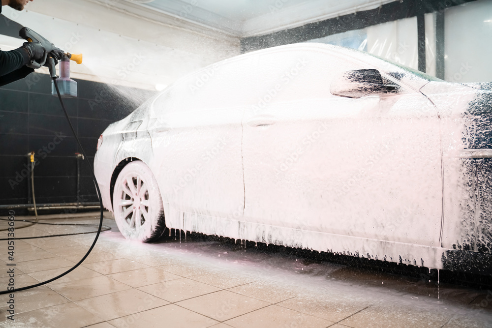 Car wash employee applies foam to the car. Professional auto wash