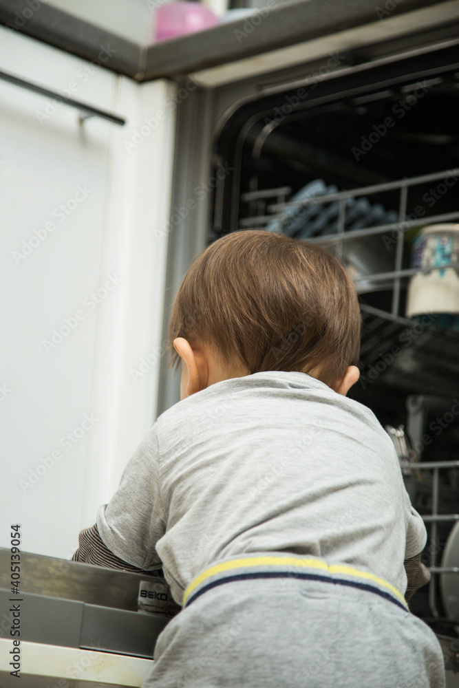 Little child boy toddler helping mom to disassemble the dishwasher. The dishwasher is open, the child is sitting next to him and holding clean dishes in his hands.
Little child boy toddler helping mom to disassemble the dishwasher. The dishwasher is open, the child is sitting next to him and holding clean dishes in his hands.
