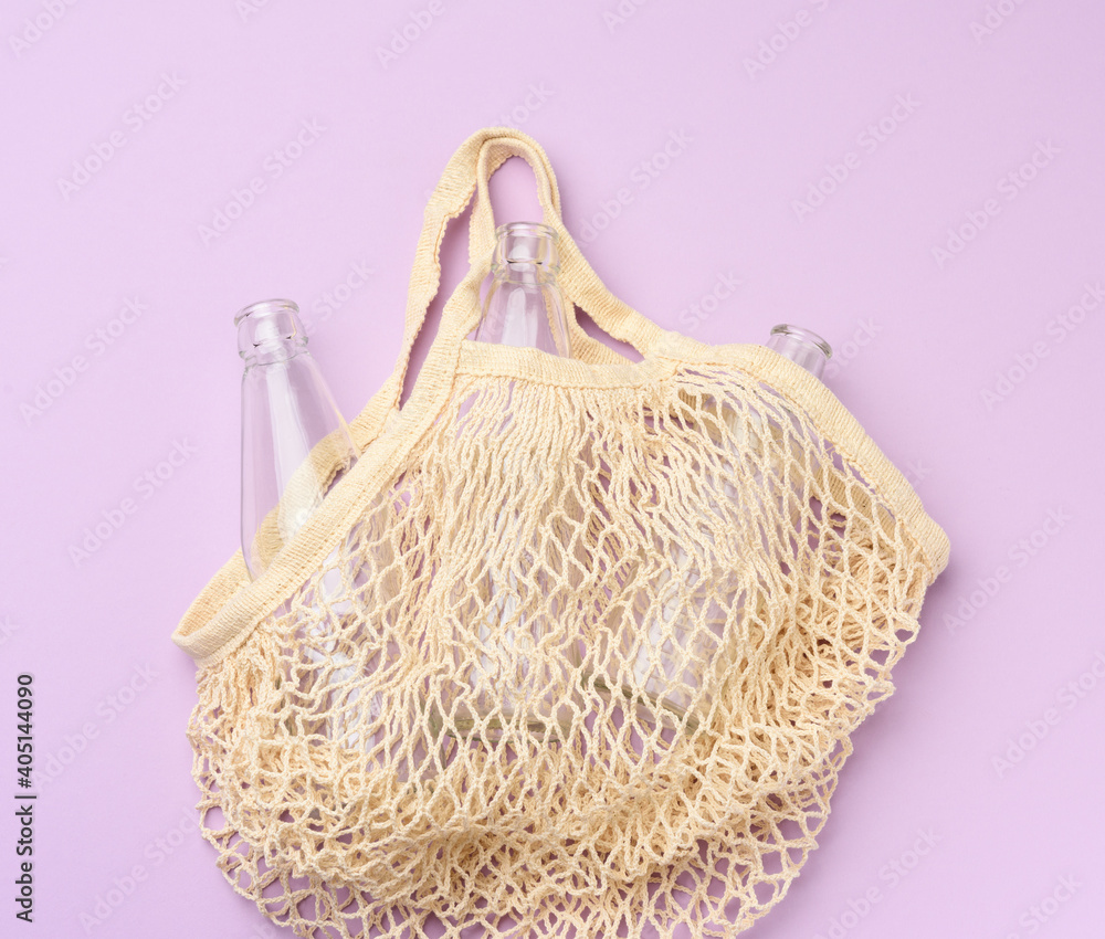 Fototapeta premium reusable textile shopping bag with empty bottles on a purple background