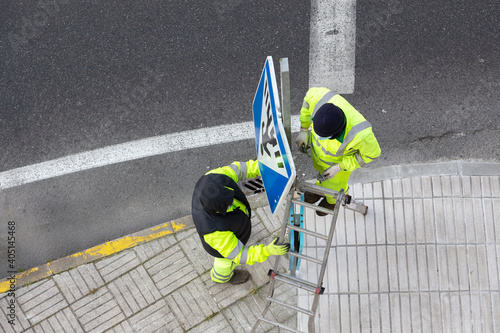 Workers changing a damaged road sign on street sidewalk