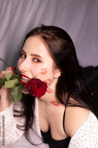 sexy brunette woman with kisses, lipstick marks on her face and neck, with red rose. girlfriend, date, relashionship. lesbian gay. lgbt