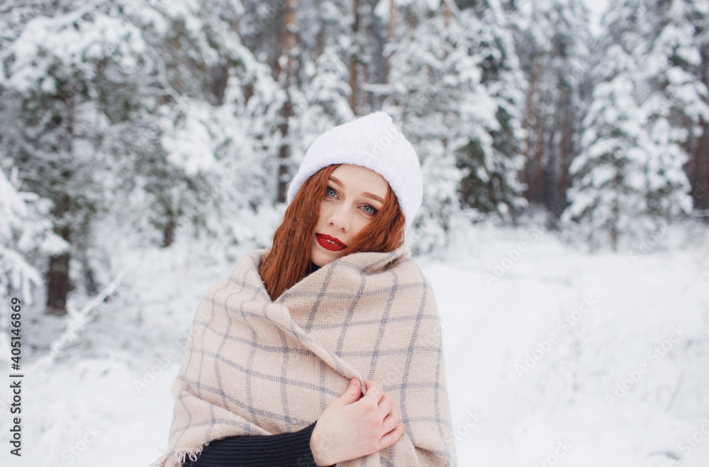 a girl with bright red hair stands in a snowy forest. a girl with bright red hair stands in a snowy forest.