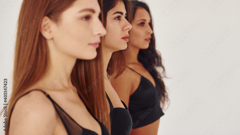 Side view. Three young women in lingerie together indoors. White background Side view. Three young women in lingerie together indoors. White background