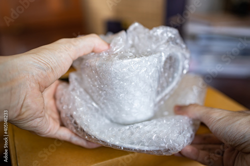 Obraz na płótnie Wrapping a ceramic cup with bubble wrap