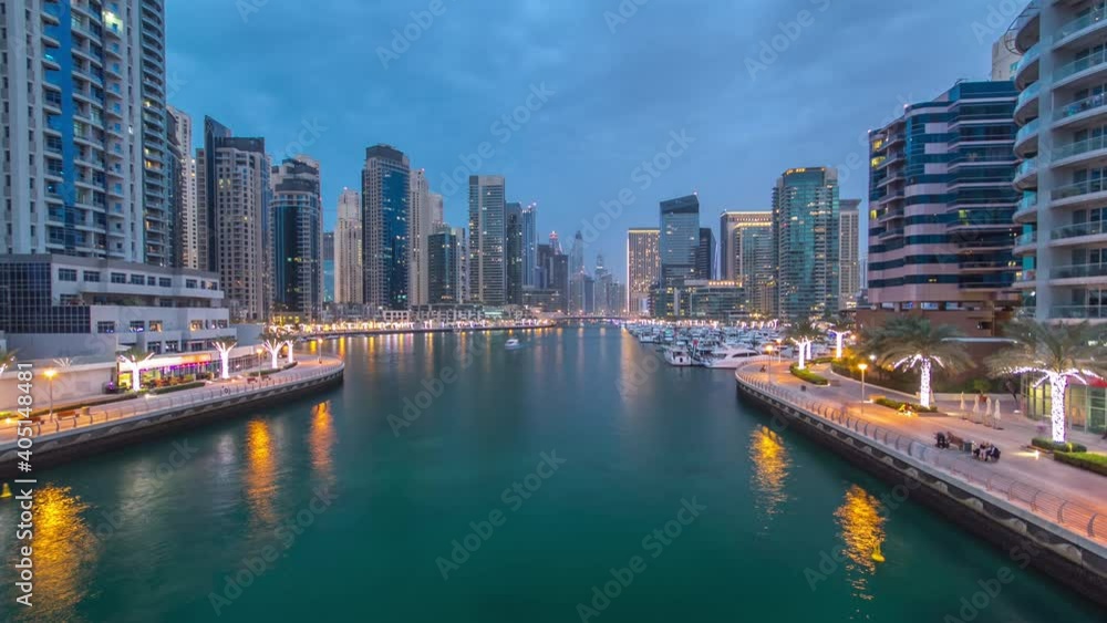 Dubai Marina waterfront with towers and yachts aerial view from bridge in Dubai day to night transition timelapse, United Arab Emirates. Dubai Marina is a district in Dubai and an artificial canal Dubai Marina waterfront with towers and yachts aerial view from bridge in Dubai day to night transition timelapse, United Arab Emirates. Dubai Marina is a district in Dubai and an artificial canal