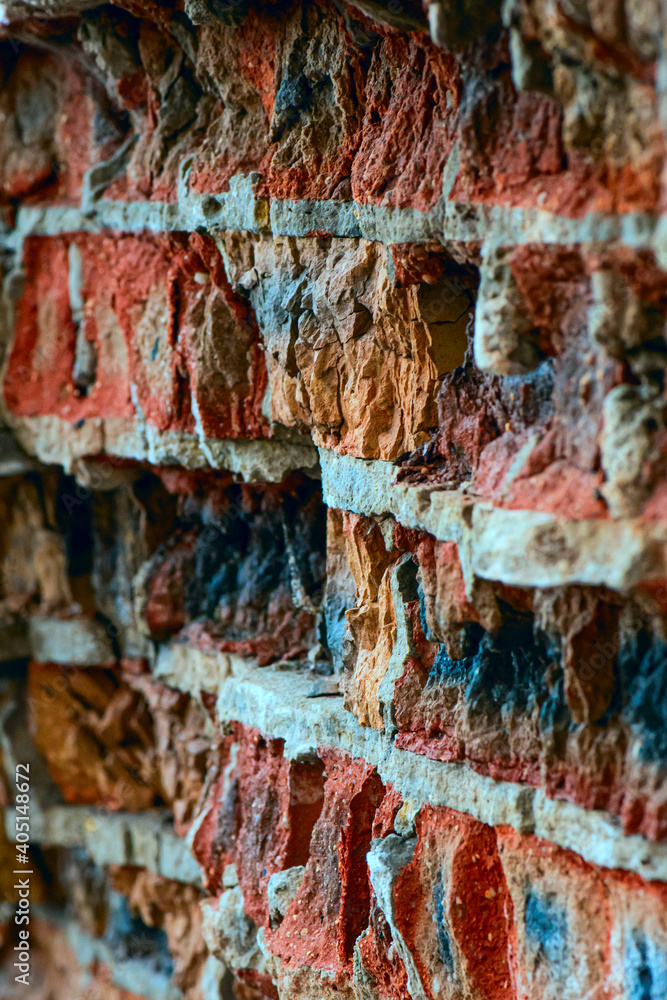 Old crumbling red brick wall. Grunge background. Selective focus. Side view. Vertical orientation.