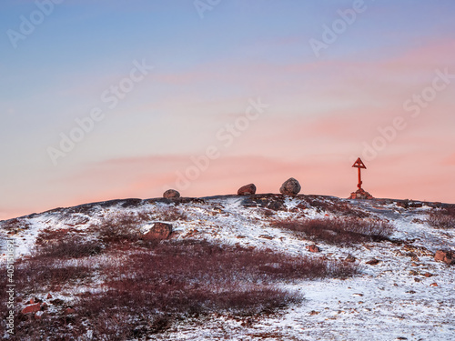 Cross on the Kola Peninsula, cold dawn in Teriberka. Balancing Rock on the Arctic hill.