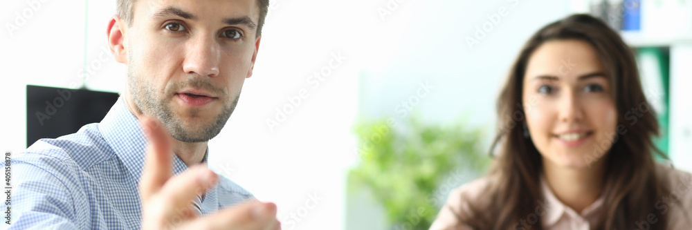 Jolly female is sitting at table with documents while annoyed man is gesturing to camera Jolly female is sitting at table with documents while annoyed man is gesturing to camera