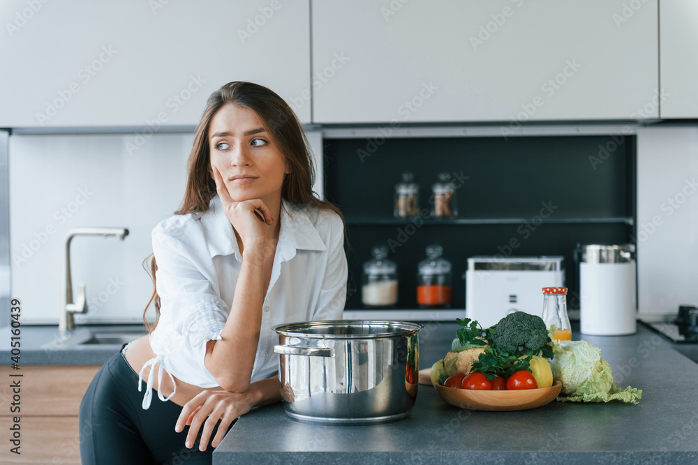 Preparation of meal in bowl. Young european woman is indoors at kitchen indoors with healthy food