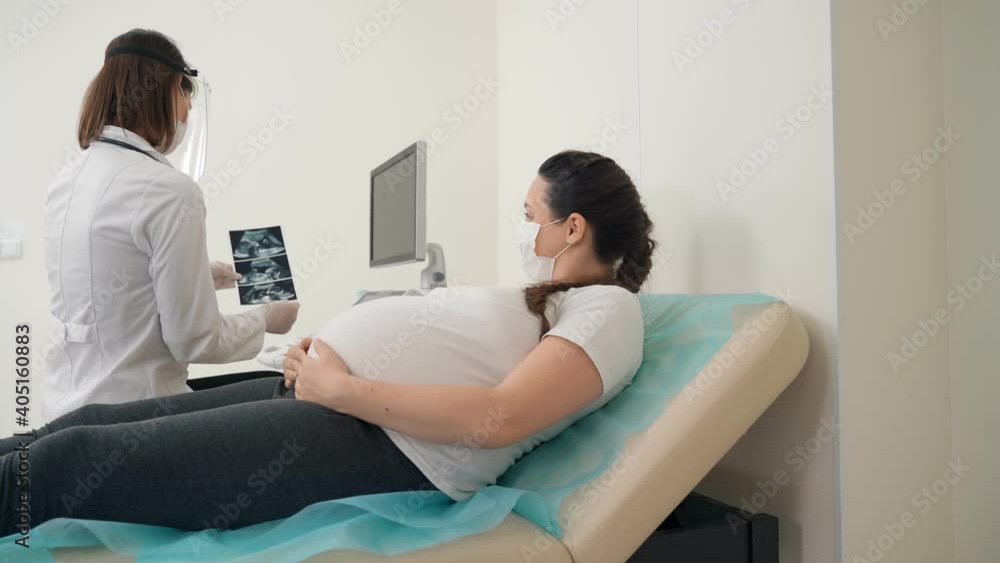 Gynecologist showing ultrasound images for pregnant woman Gynecologist showing ultrasound images for pregnant woman
