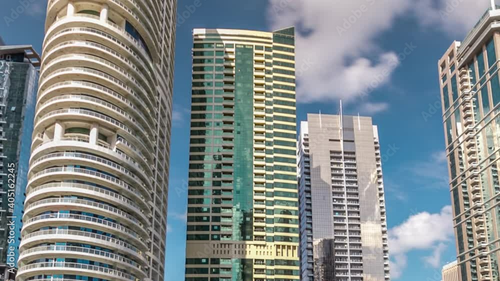 Hyperlapse view on skyscrapers at waterfront. Residential buildings in Jumeirah Lake Towers reflected in water timelapse in Dubai, UAE. View with blue cloudy sky from embankment Hyperlapse view on skyscrapers at waterfront. Residential buildings in Jumeirah Lake Towers reflected in water timelapse in Dubai, UAE. View with blue cloudy sky from embankment