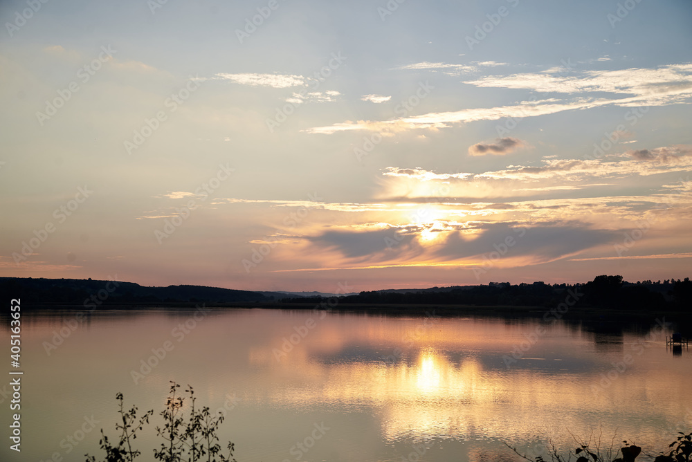 Beautiful lake view during sunset with blue and yellow sky reflection in water. Rural scene. Ecological protection and eco tourism concept. Natural landscape. Isolation in countryside.