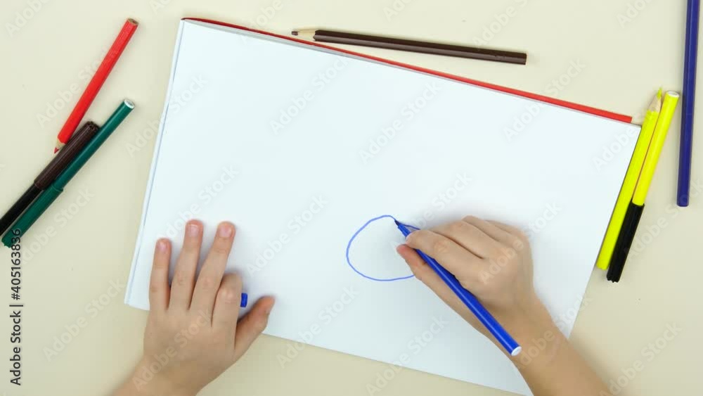 Hands of a child close-up drawing a happy person on paper. The child draws a family. Time for games and entertainment. Family values.