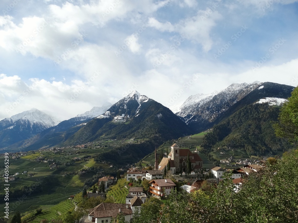 Blick auf Schenna in Südtirol von erhöhtem Standort mit Bergpanorama im Hintergrund bei blauem Himmel mit weissen Wolken