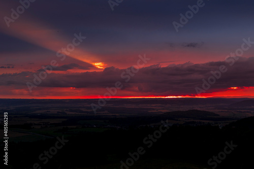 The landscape of the Beskydy Mountains from the viewpoint near Jicin during a colorful sunset and dark clouds in the sky and a view of the surrounding landscape.