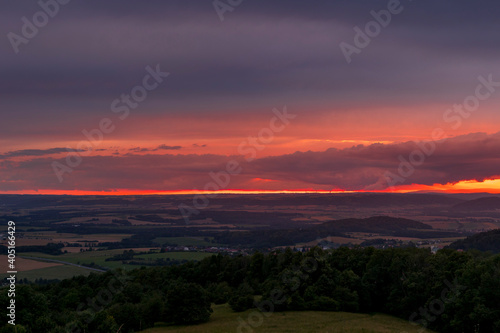 The landscape of the Beskydy Mountains from the viewpoint near Jicin during a colorful sunset and dark clouds in the sky and a view of the surrounding landscape.