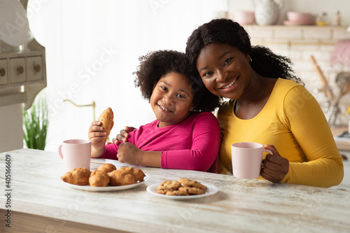 African mother and little daughter having a bite in kitchen together