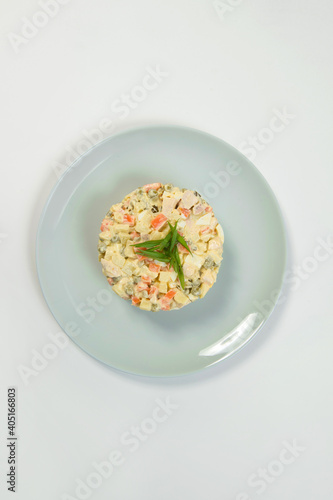 Top view of Russian traditional holiday Olivier salad. Dish of boiled vegetables dressed with mayonnaise sauce. Christmas New Year cold dish served on gray plate. Object isolated on background. 