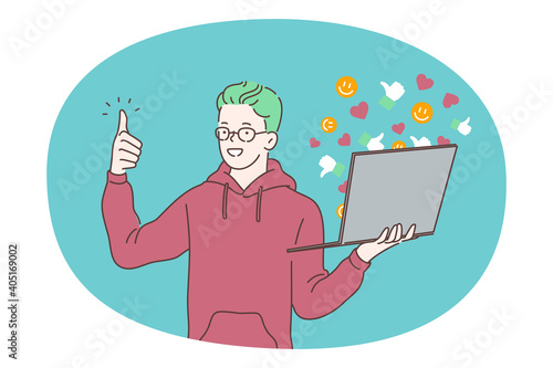Online communication, e-learning, laptop concept. Young smiling boy standing with laptop and showing thumbs up sign with finger. Communicating online with friends, studying, watching distant courses 