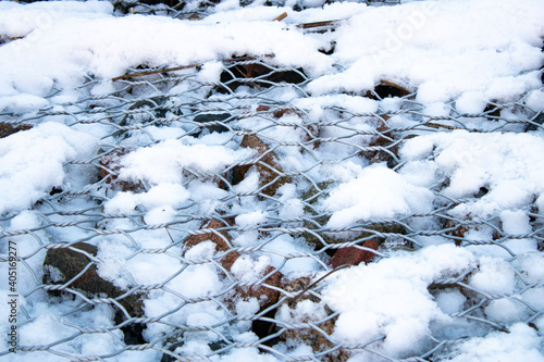 iron mesh covered with snow © Anastasija