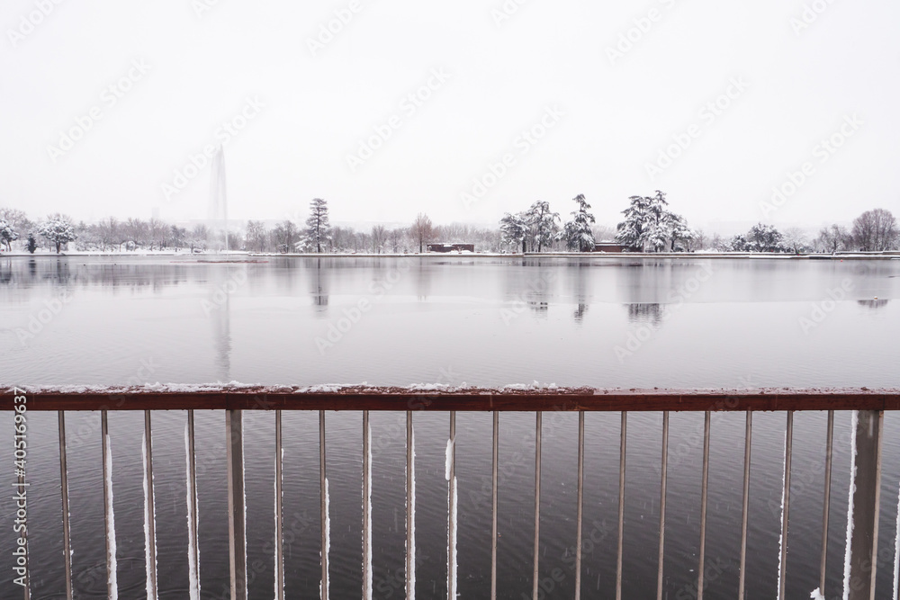 View to the lake of the “Casa de Campo” park in Madrid, from the railing, with the horizon covered by snow, during “Filomena” storm. 