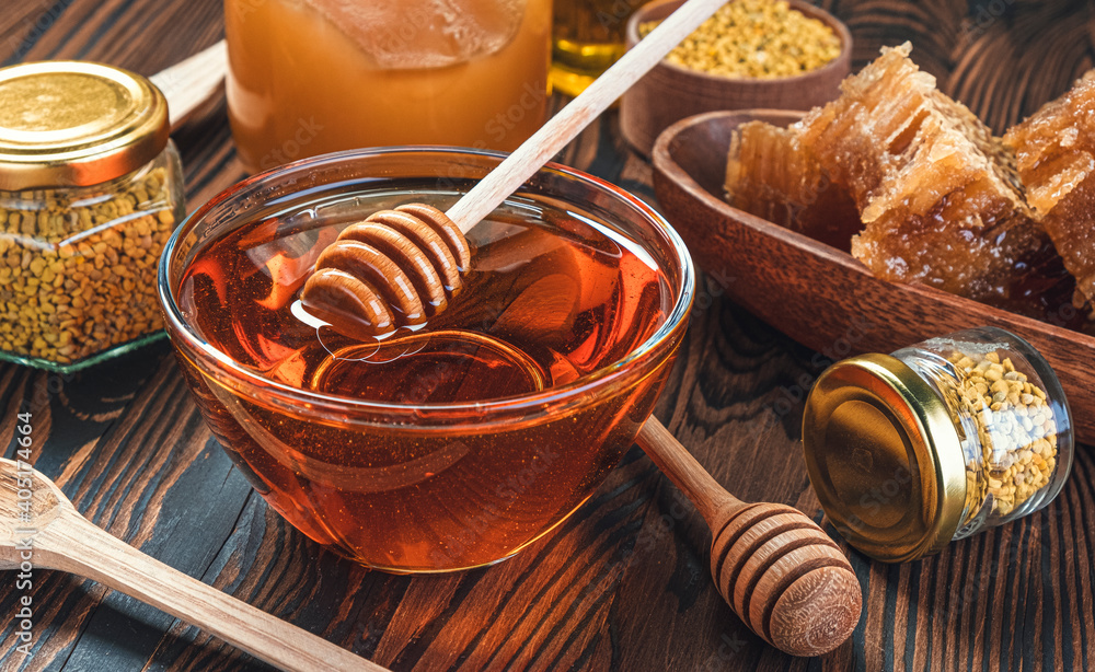 Honey in glass jar with honey dipper over wooden background Honey in glass jar with honey dipper over wooden background