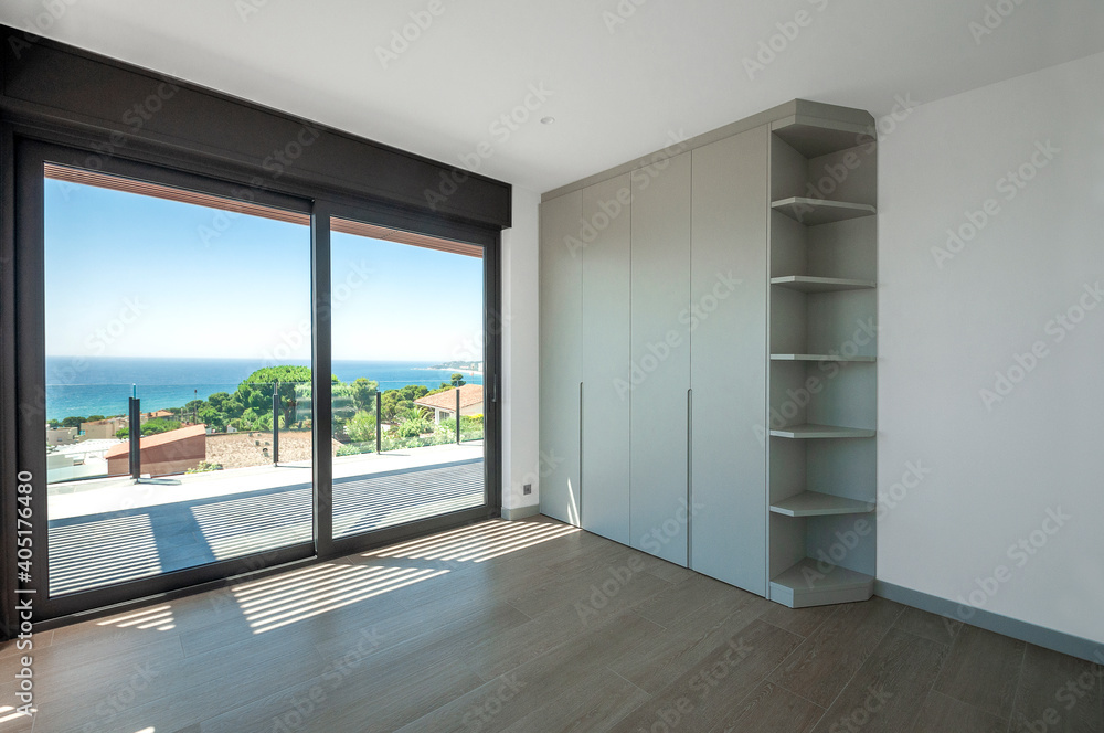 Empty room with large panoramic windows overlooking the sea. Room after major renovation.