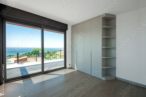 Empty room with large panoramic windows overlooking the sea. Room after major renovation.