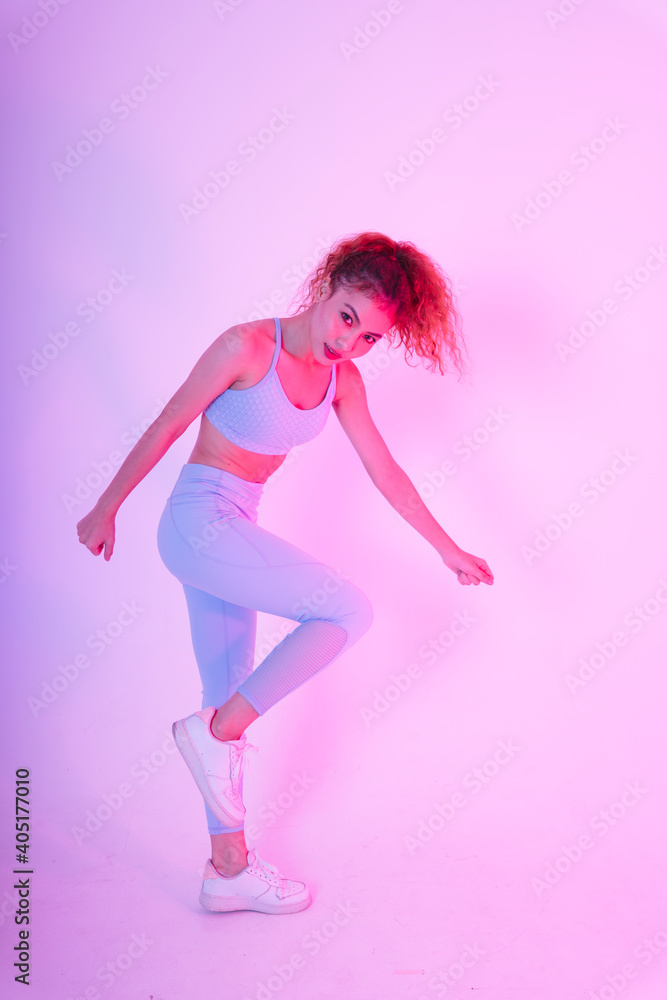 Sporty young asian woman in exercise outfit stretching body in neon studio light.