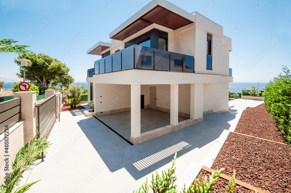 The facade of the modern house is from the side, and the organization of the yard and garden. Parking space in the house.