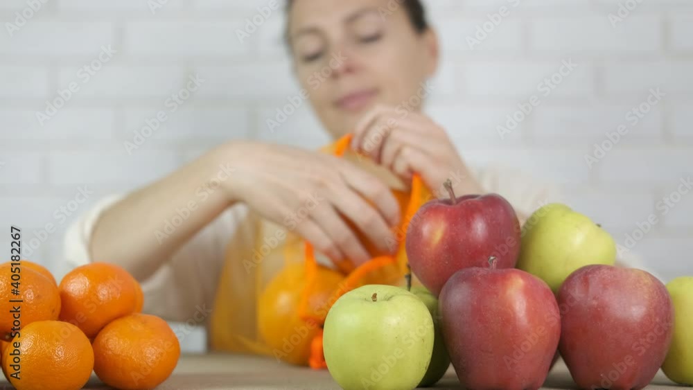 Eco shopper. Woman puts fruits in a reusable bag. Eco shopper. Woman puts fruits in a reusable bag.