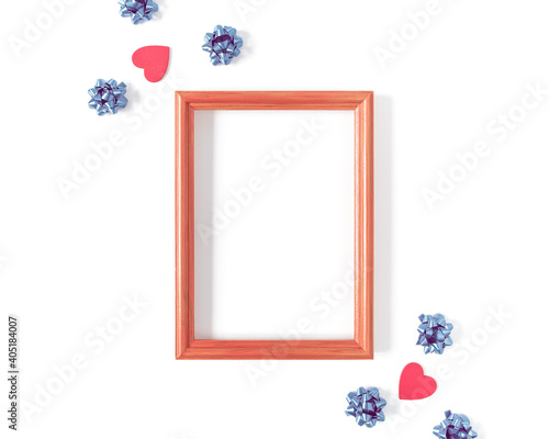 Empty wooden photo frame, red shapes in the form of hearts, blue bows are on a white background. Composition for Valentine's Day. Flat lay. Top view. Copy space.