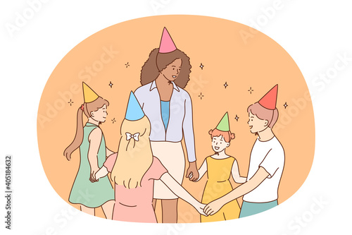 Children, birthday party, friendship concept. Group of smiling cheerful children friends in festive caps holding hands and celebrating birthday with teacher mother or nanny together