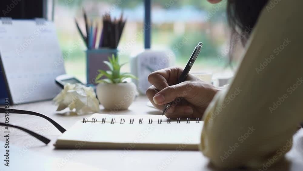 Working from home concept. Hand of Planner write timetable and daily agenda on calendar book. Woman mark and noted schedule (holiday trip) on diary at home office desk. Working from home concept. Hand of Planner write timetable and daily agenda on calendar book. Woman mark and noted schedule (holiday trip) on diary at home office desk.