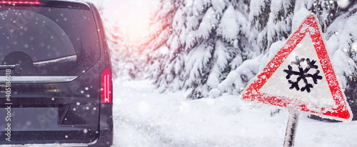 snowfall warning sign. a car off the road in winter photo