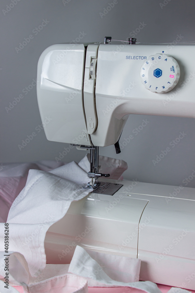 White sewing machine on a pink background. Electric sewing machine. white fabric on the sewing machine. Handmade tool. Sewing business.